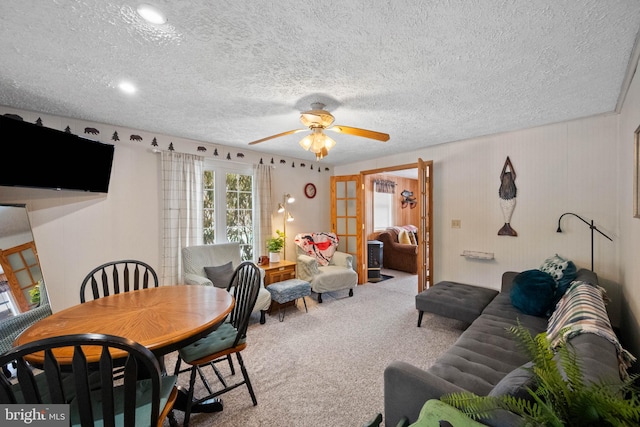 carpeted dining space featuring french doors, ceiling fan, and a textured ceiling