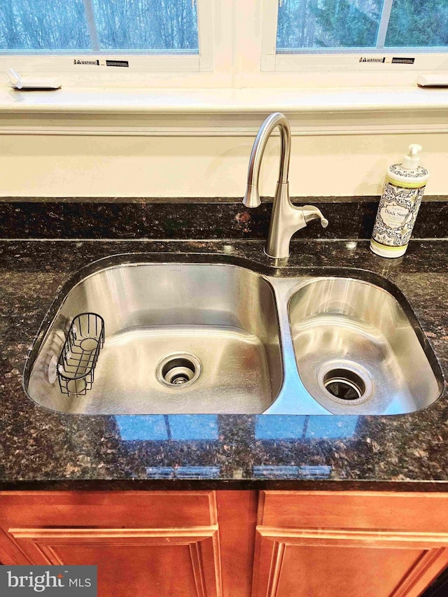 interior details featuring sink and dark stone countertops