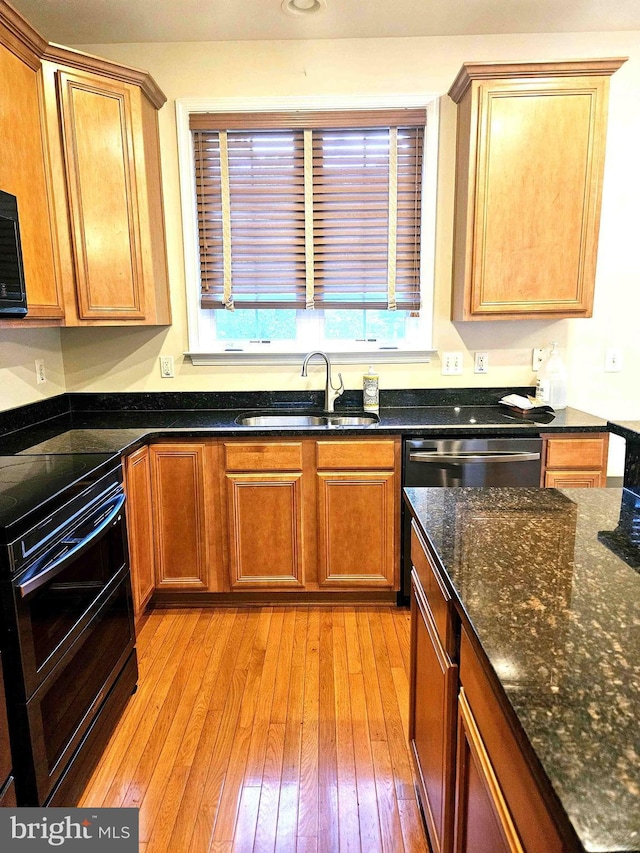 kitchen featuring stainless steel appliances, sink, dark stone countertops, and light wood-type flooring