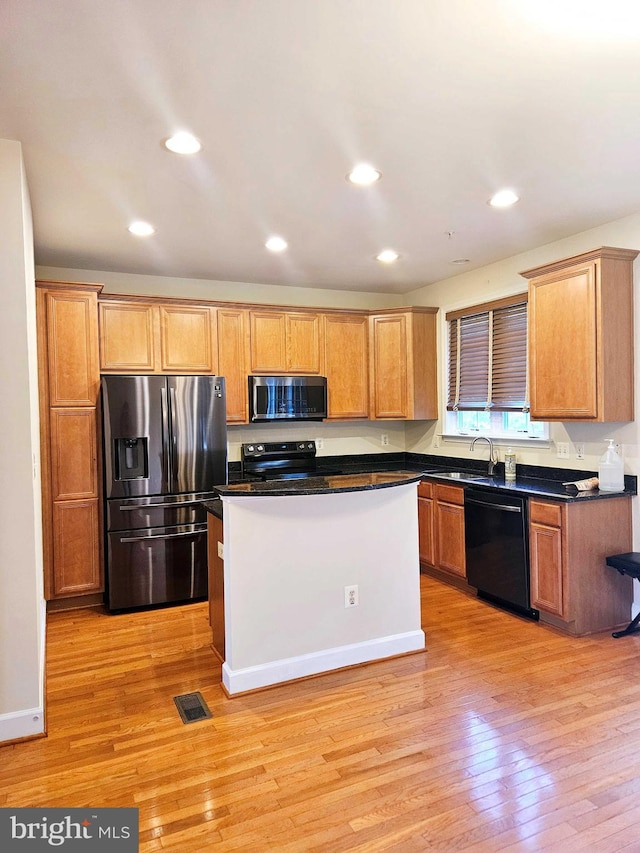 kitchen featuring sink, a center island, light hardwood / wood-style floors, and black appliances