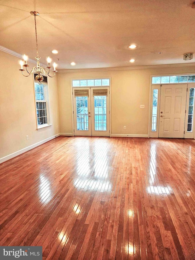 interior space featuring crown molding, wood-type flooring, a notable chandelier, and french doors