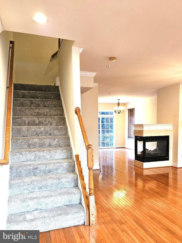 stairs featuring hardwood / wood-style floors and a multi sided fireplace