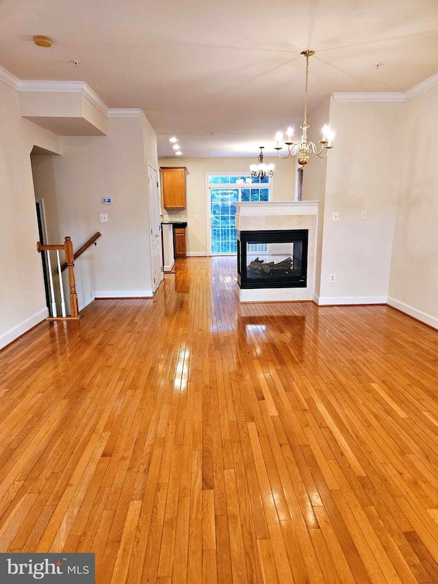 unfurnished living room with crown molding, a multi sided fireplace, and light wood-type flooring