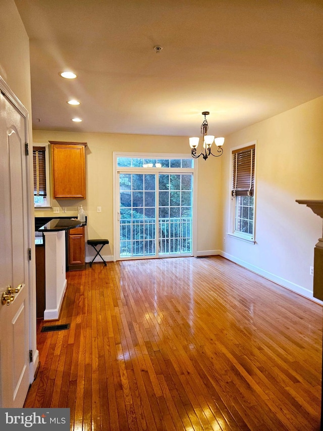 unfurnished living room with an inviting chandelier and dark hardwood / wood-style flooring