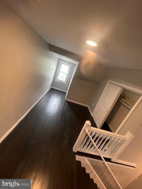 additional living space featuring lofted ceiling and dark hardwood / wood-style flooring