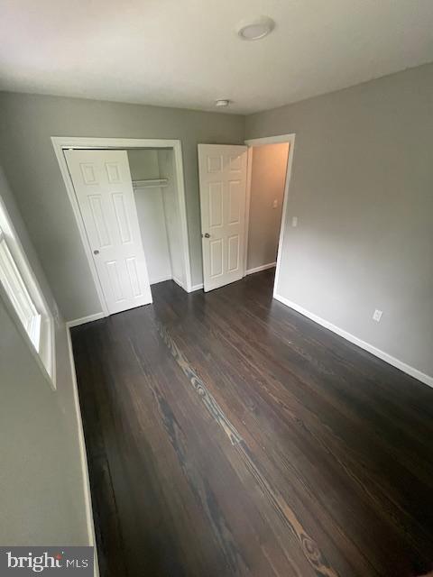 unfurnished bedroom featuring a closet and dark hardwood / wood-style floors