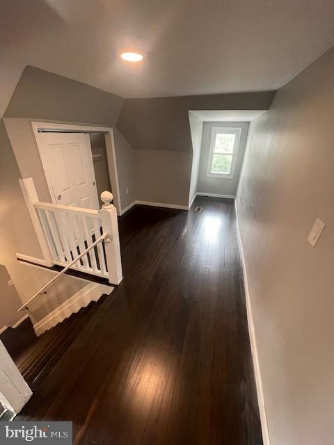 additional living space with dark wood-type flooring and lofted ceiling