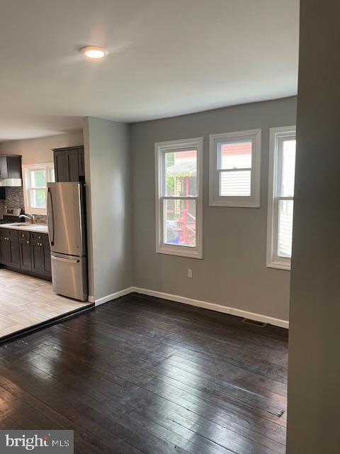 interior space featuring stainless steel fridge, decorative backsplash, light hardwood / wood-style flooring, dark brown cabinetry, and sink