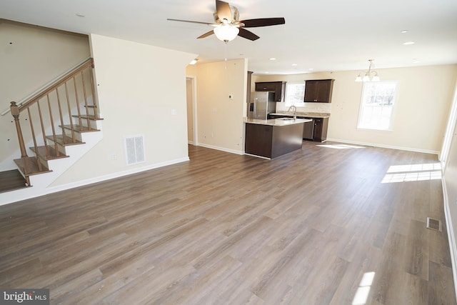 unfurnished living room featuring dark hardwood / wood-style flooring and ceiling fan with notable chandelier