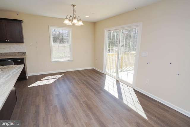 unfurnished dining area featuring dark wood-type flooring and a chandelier