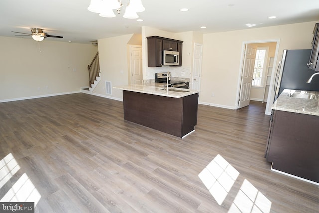 kitchen featuring hardwood / wood-style floors, sink, light stone countertops, stainless steel appliances, and dark brown cabinets