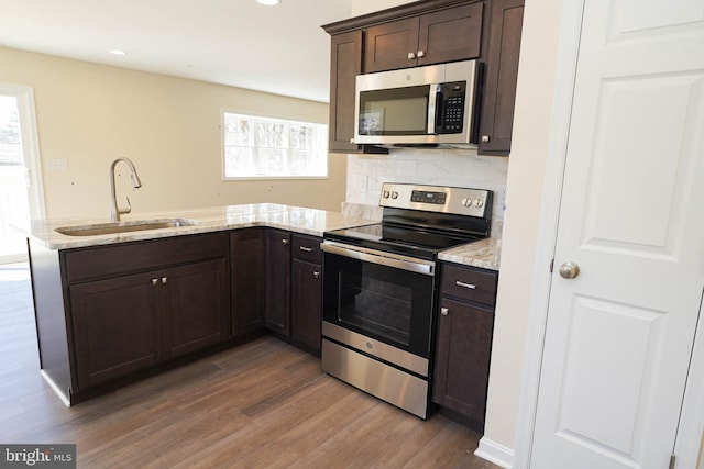 kitchen with a wealth of natural light, appliances with stainless steel finishes, dark hardwood / wood-style flooring, and sink