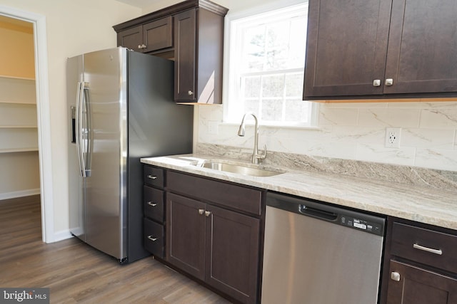 kitchen with dark brown cabinetry, wood-type flooring, stainless steel appliances, decorative backsplash, and sink