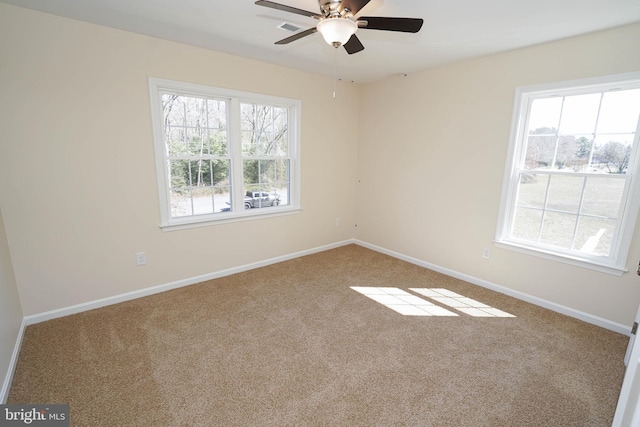 carpeted spare room featuring ceiling fan and a healthy amount of sunlight