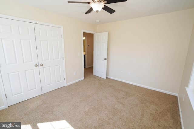 unfurnished bedroom featuring ceiling fan, light colored carpet, and a closet