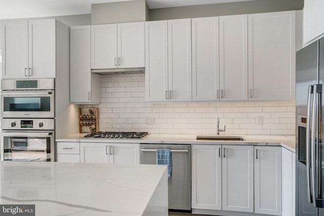 kitchen with stainless steel appliances, backsplash, white cabinets, and sink