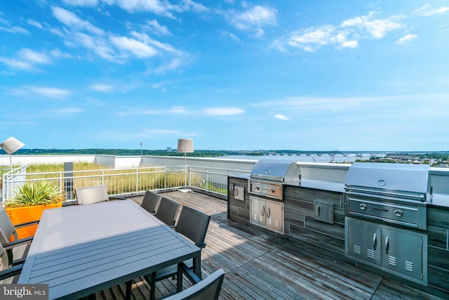 wooden terrace with a water view, an outdoor kitchen, and grilling area