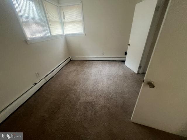 empty room with carpet floors and a baseboard radiator