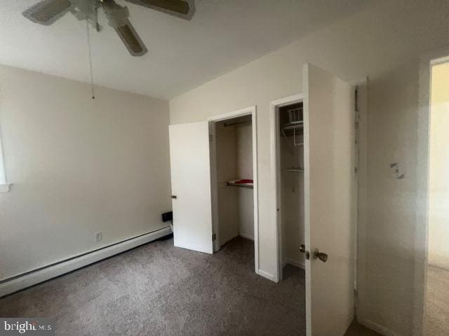 unfurnished bedroom with ceiling fan, a spacious closet, a closet, dark carpet, and a baseboard radiator