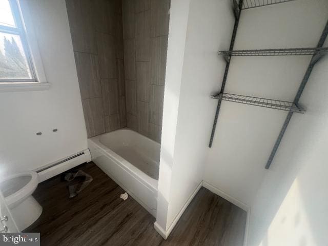 bathroom with tub / shower combination, wood-type flooring, a baseboard heating unit, and toilet