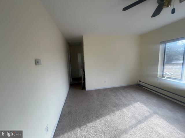 carpeted empty room with a baseboard heating unit and ceiling fan