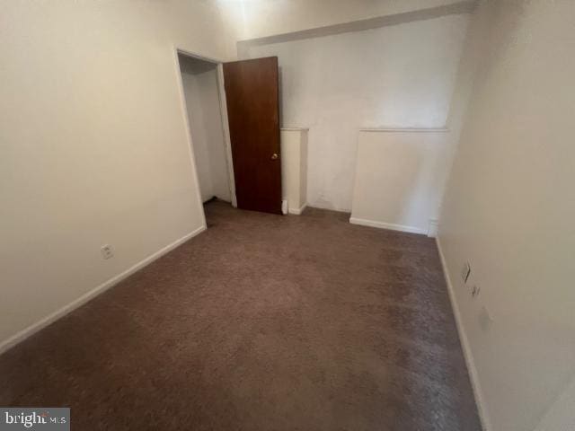 spare room featuring dark carpet