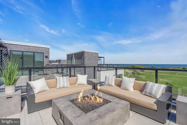 view of patio / terrace with a water view, a balcony, and an outdoor living space with a fire pit