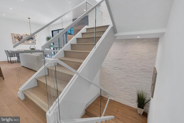 staircase featuring hardwood / wood-style flooring and a notable chandelier