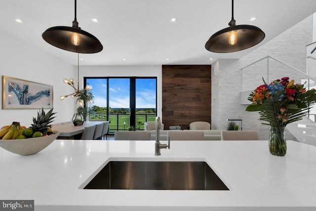 kitchen featuring sink, hanging light fixtures, and wood walls