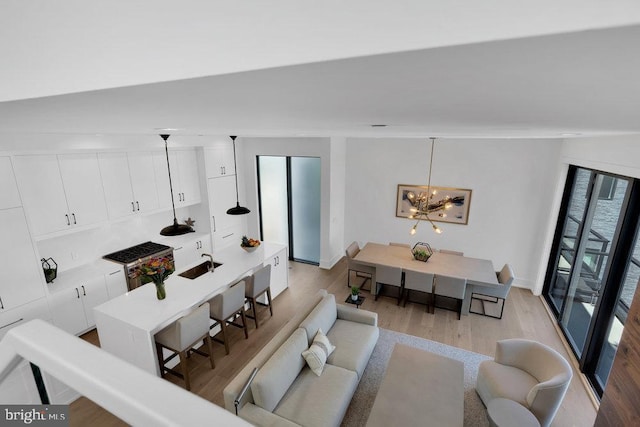 living room with sink, a notable chandelier, and light hardwood / wood-style floors