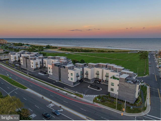 aerial view at dusk with a view of the beach and a water view