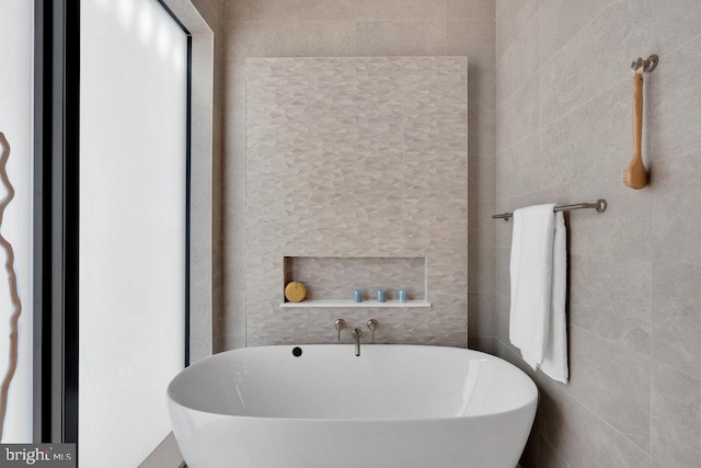 bathroom featuring a washtub and tile walls