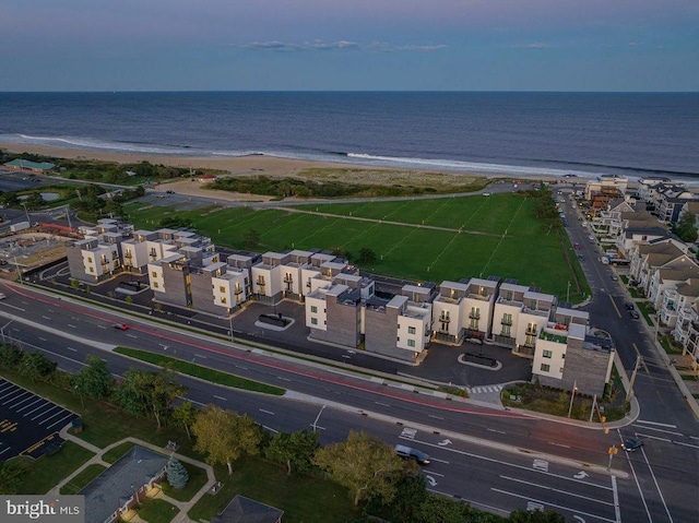 aerial view at dusk with a water view and a view of the beach