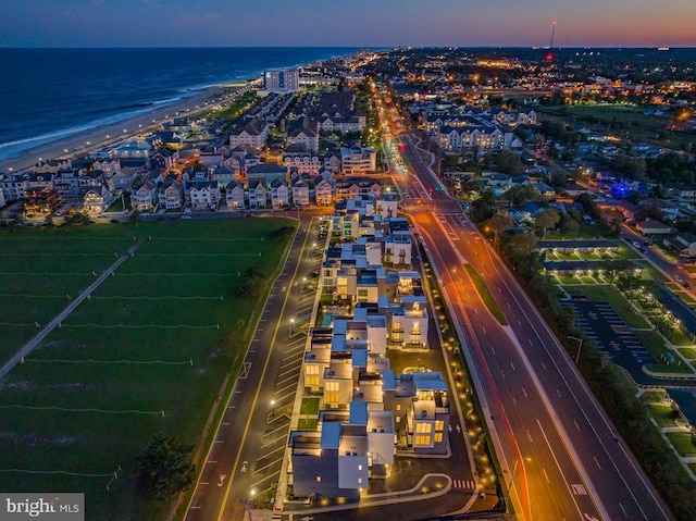 aerial view at dusk featuring a beach view and a water view