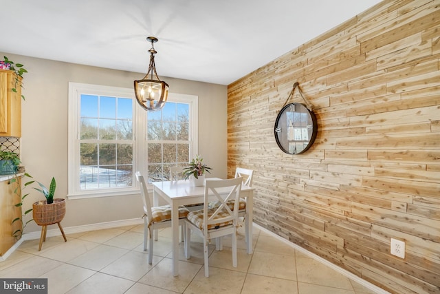 tiled dining space featuring a chandelier and wood walls