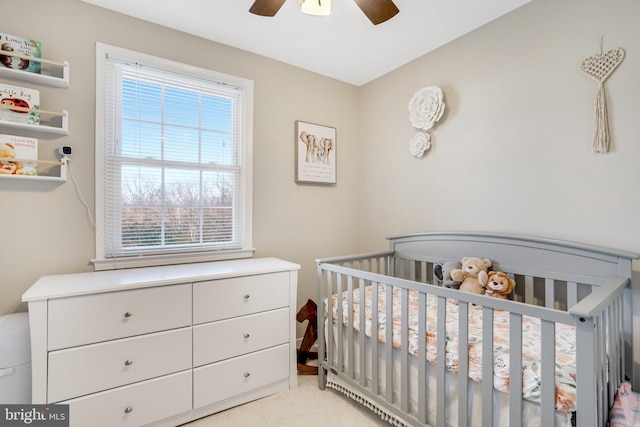 bedroom with a nursery area and ceiling fan