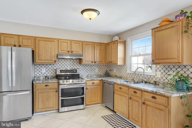 kitchen with sink, light tile patterned floors, appliances with stainless steel finishes, backsplash, and light stone counters