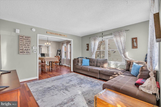 living room featuring dark wood-type flooring, a textured ceiling, and a notable chandelier