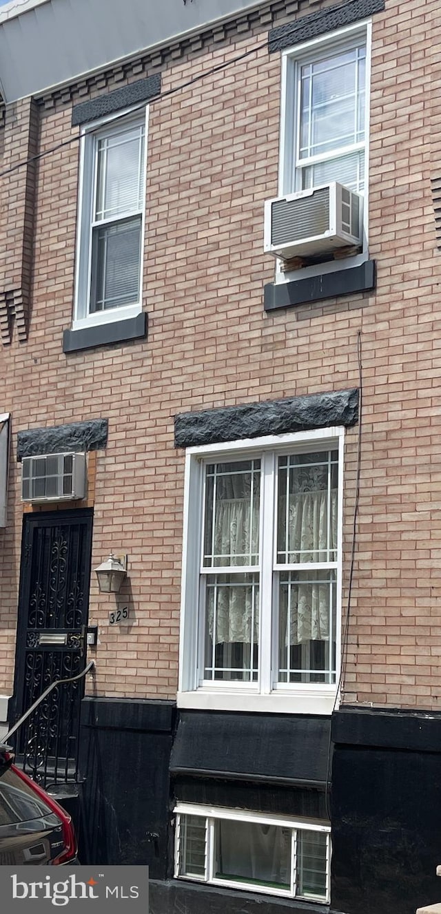 view of property exterior with cooling unit, brick siding, and an AC wall unit