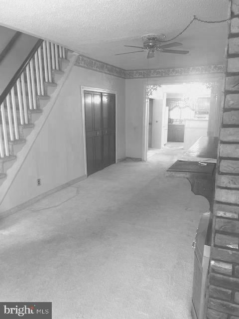 unfurnished living room featuring ceiling fan, carpet, and a textured ceiling