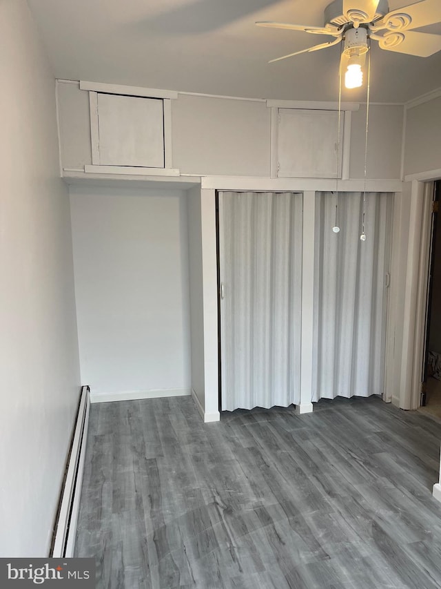 interior space with attic access, baseboard heating, and wood finished floors