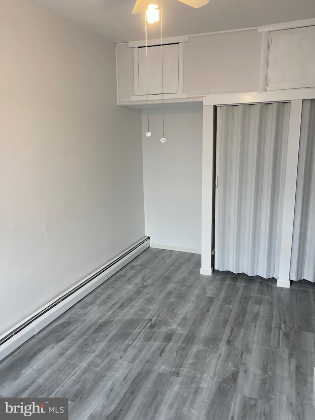 unfurnished room featuring ceiling fan, a baseboard heating unit, and dark wood finished floors