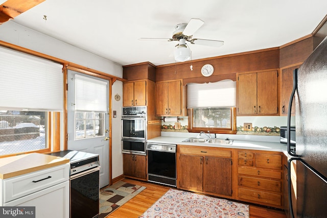 kitchen with ceiling fan, sink, light hardwood / wood-style floors, and black appliances