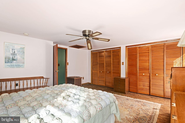 bedroom with ceiling fan, two closets, and hardwood / wood-style flooring