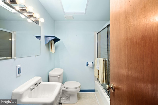 full bathroom featuring toilet, a skylight, shower / bath combination with glass door, and sink