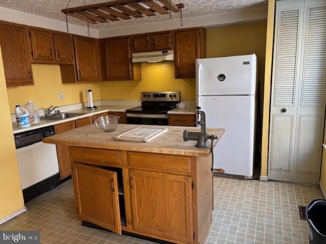 kitchen featuring sink, a center island, a textured ceiling, and stainless steel appliances