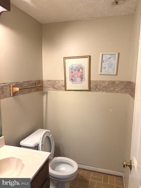 bathroom featuring vanity, toilet, tile patterned floors, and a textured ceiling