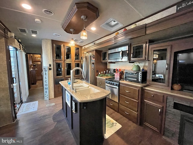 kitchen featuring a center island with sink, sink, hanging light fixtures, stainless steel appliances, and dark hardwood / wood-style flooring