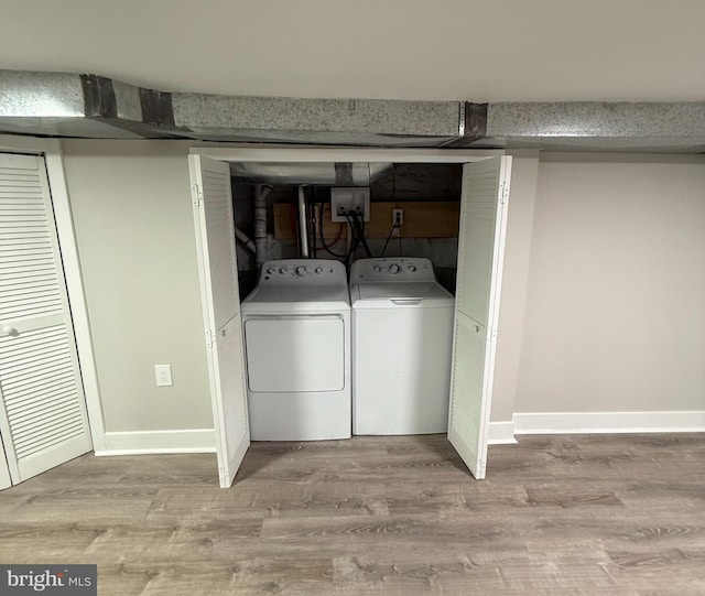 clothes washing area with light hardwood / wood-style floors and washing machine and clothes dryer