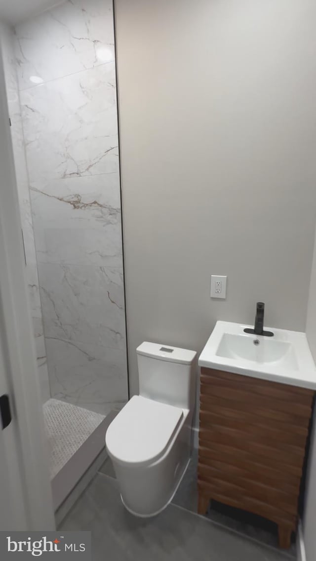 bathroom featuring tiled shower, toilet, and vanity